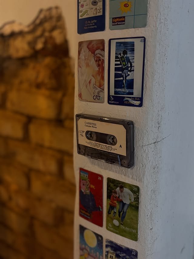 Cartoes telefonicos e fita cassete na parede